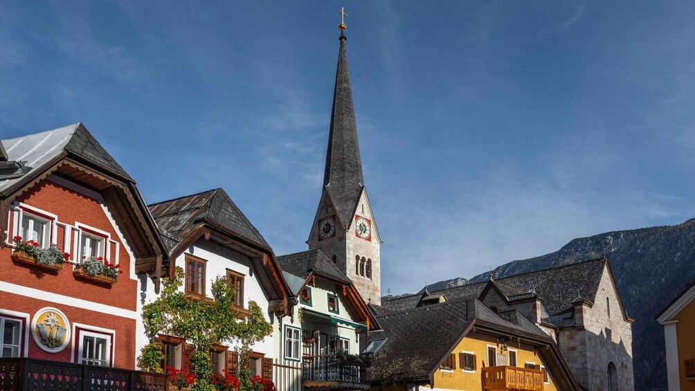 A church with a tall steeple and a clock, surrounded by traditional European buildings. 4