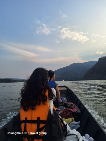 Two people on a boat with a calm river and hills in the background. 2