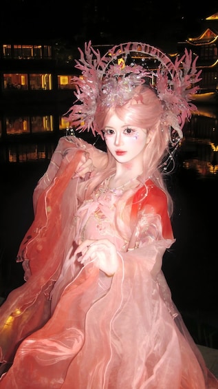 A person in a pink dress with a decorative headpiece, standing outdoors at night. 3