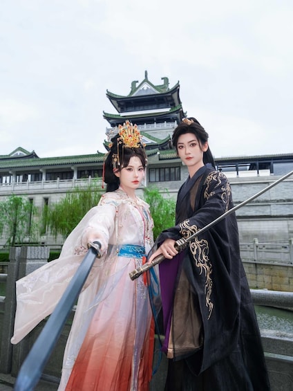 Two people in traditional costumes, a building with a green roof, and a body of water. 1