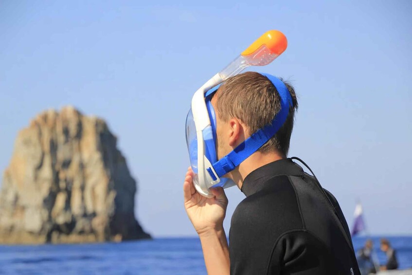 A person snorkeling with a mask and snorkel, near a rocky coastline. 5