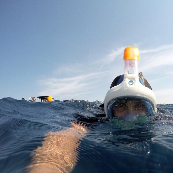 A diver in a white helmet with a yellow top, swimming in the ocean. 1
