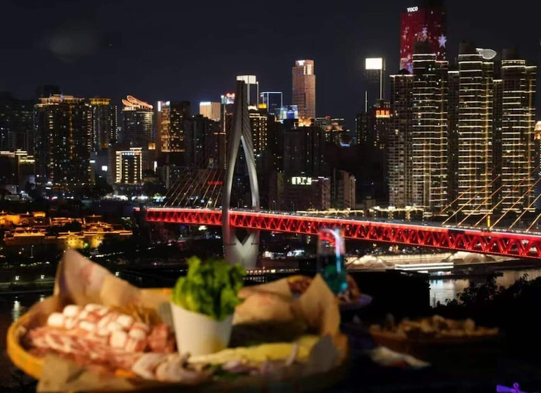 A cityscape at night with illuminated buildings and a prominent red bridge. 1