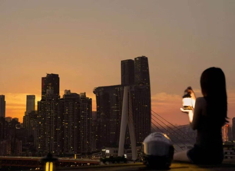 A city skyline at dusk with illuminated buildings and a bridge. 2