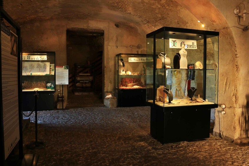 A museum exhibit with glass display cases containing historical artifacts and mannequins. 3