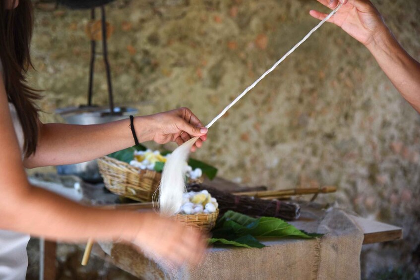 A person holding a string, possibly for a game or activity, with baskets and leaves in the background. 2