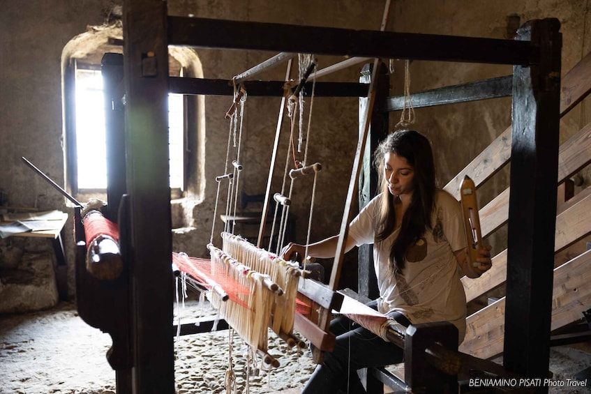 A person weaving on a traditional loom in a rustic setting. 5