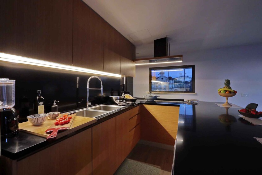 A modern kitchen with wooden cabinets, a black countertop, and a window with a cityscape view. 4