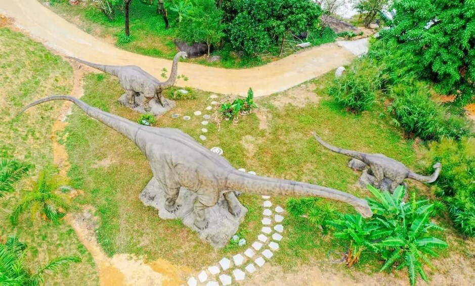 A dinosaur exhibit with three models in a garden setting. 4