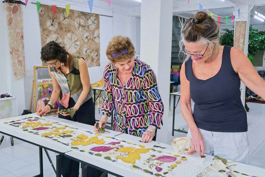 Three people working on a table with floral patterns. 3
