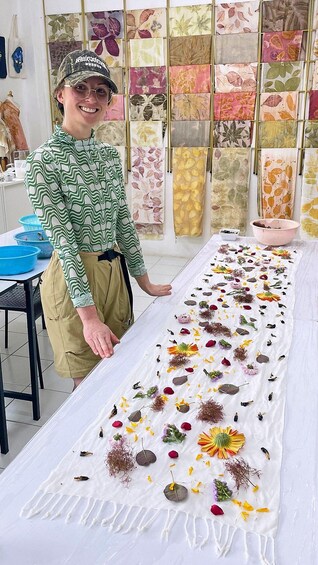 A person standing next to a table with a variety of dried flowers and leaves displayed on it. 2