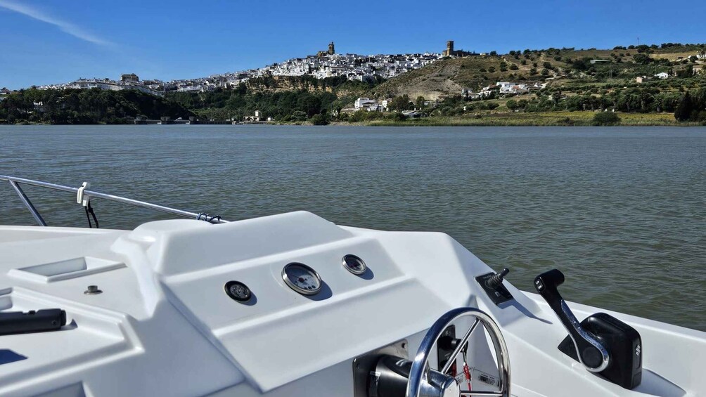 A boat's cabin with a view of a hilltop town across the water. 5
