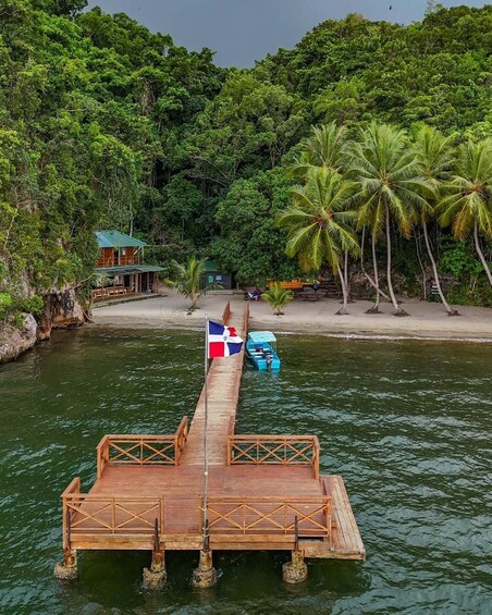 A wooden pier extending into a river, with a flag, a small boat, and a cabin in the background. 5