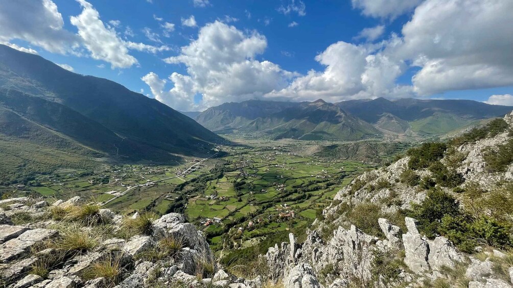 A mountainous landscape with a valley, scattered houses, and rocky terrain. 2