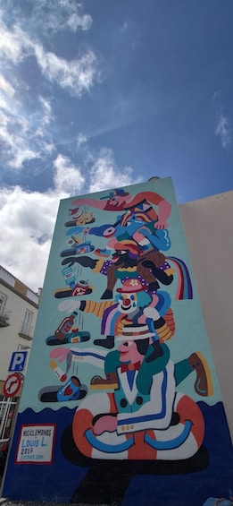 A colorful mural on a building with various figures and symbols, including a sign that reads 'RECICLEMONDOS LOUIS L. 2017.' 4