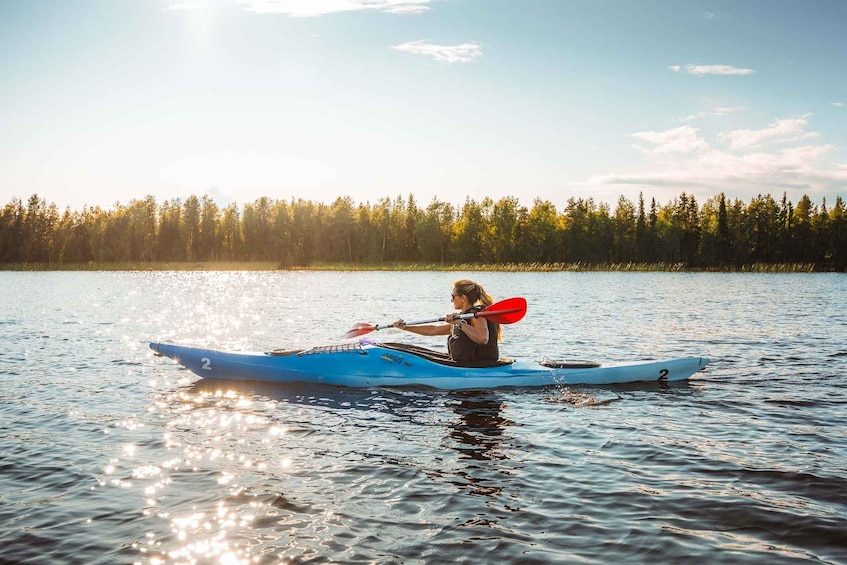 A person kayaking on a calm lake with a forest in the background. 1