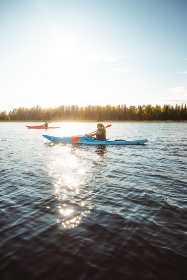 Two kayakers on a calm lake with a forest in the background. 4