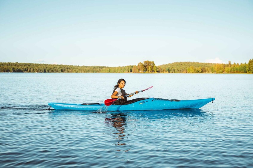 A person kayaking on a calm lake with a forested shoreline. 3