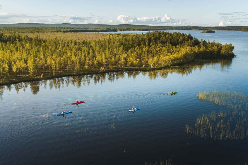 A calm lake with kayaks, surrounded by dense forest and distant hills. 2
