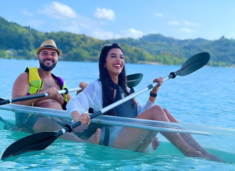 Two people kayaking on a calm lake with hills in the background. 1