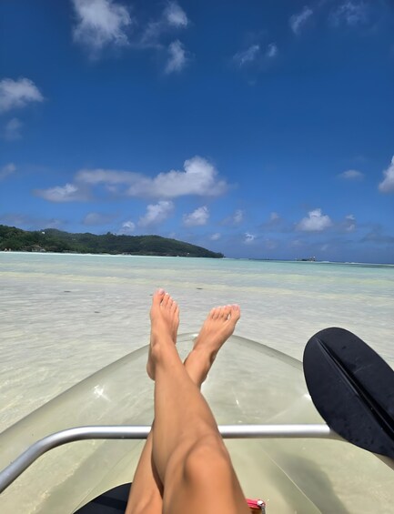 A pair of legs resting on a boat with a clear blue sky and turquoise sea in the background. 2