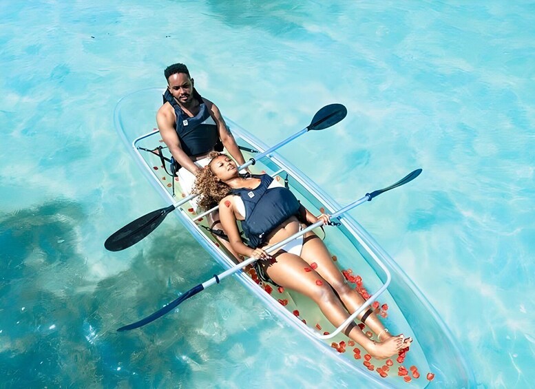 A couple in a transparent kayak on clear blue water. 3