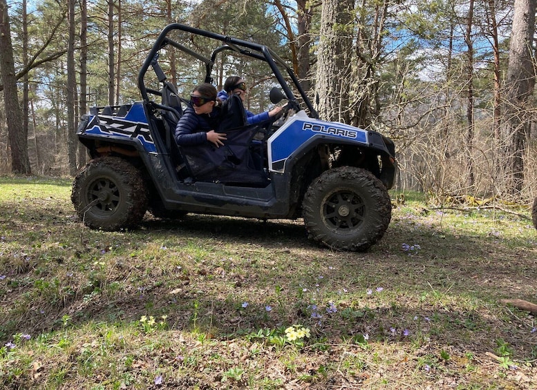 A Polaris off-road vehicle in a forested area with muddy terrain. 2