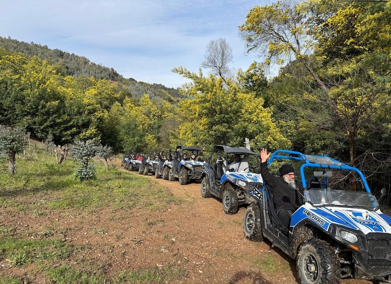 A line of ATVs on a dirt path surrounded by trees and hills. 1