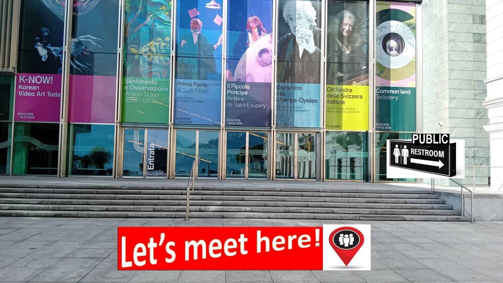 A building with large glass windows displaying various posters and a sign indicating a public restroom. 2