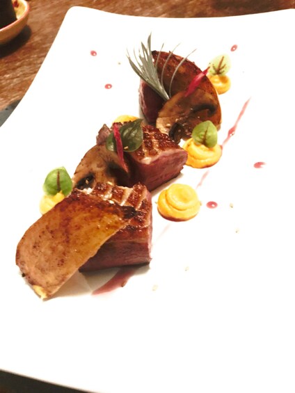 A plated dish with meat, garnishes, and sauce. 3