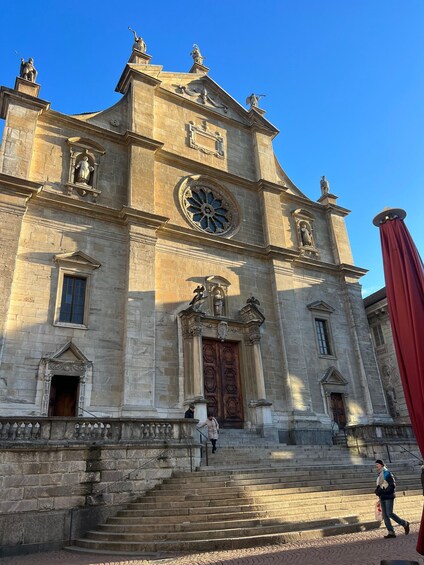 A historic building with a large circular window, statues, and a prominent wooden door. 4