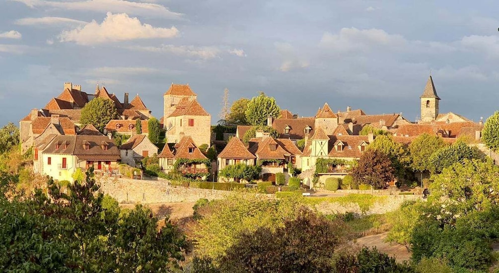 A historic village with traditional architecture, a church tower, and a stone wall. 1