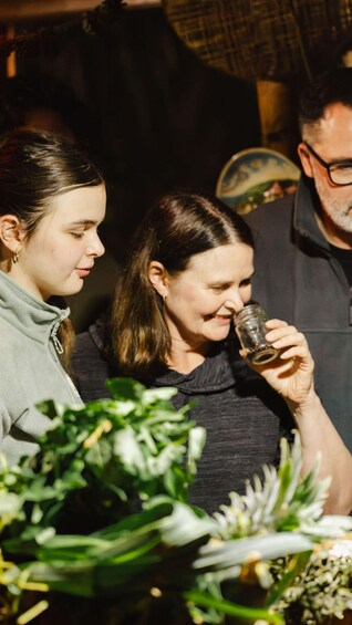 A person holding a glass, with greenery in the foreground. 1