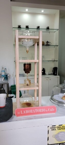 A café with a wooden display shelf, a coffee machine, and a sign reading 'El Laboratorio de Café'. 4