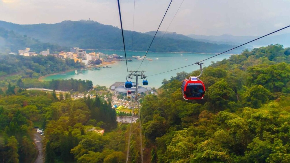 A cable car system, lush greenery, a coastal town, and a mountain backdrop. 5