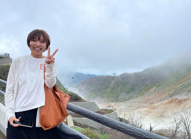 A person standing on a railing with a mountainous landscape in the background. 1