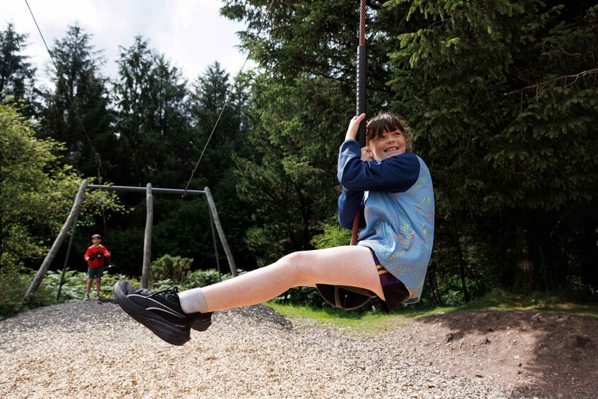 A person swinging on a rope swing in a wooded area. 2