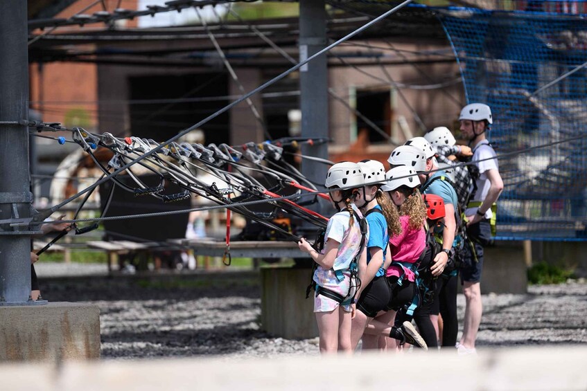 A group of people with helmets and harnesses, preparing for an activity involving ropes and cables. 2