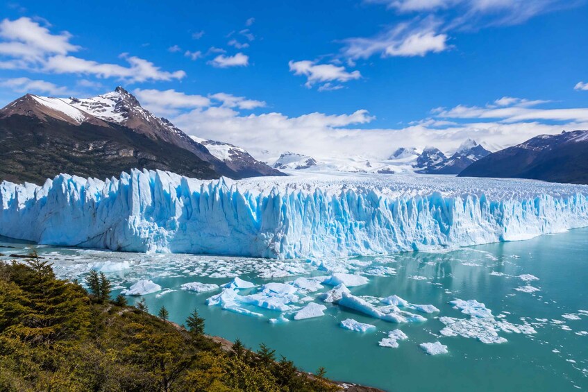 A glacier with icebergs in a turquoise lake, surrounded by mountains. 1