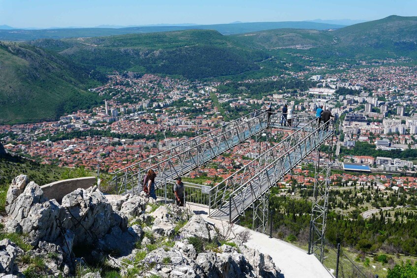 A cityscape with a pedestrian bridge over a valley. 5
