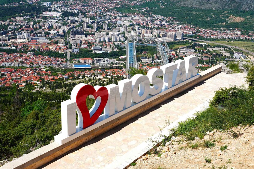 A cityscape with a prominent 'I ♥ MOSTAR' sign. 3