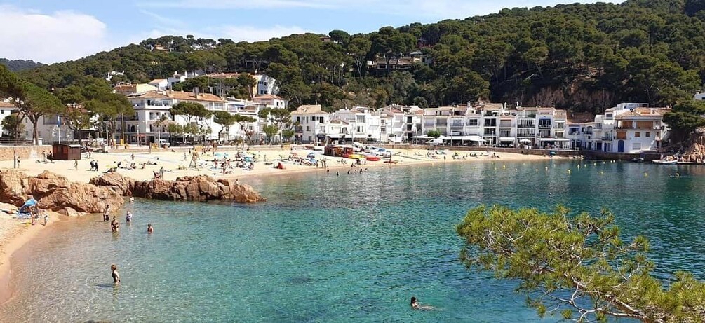 A coastal town with clear waters, a sandy beach, and buildings along the shore. 1