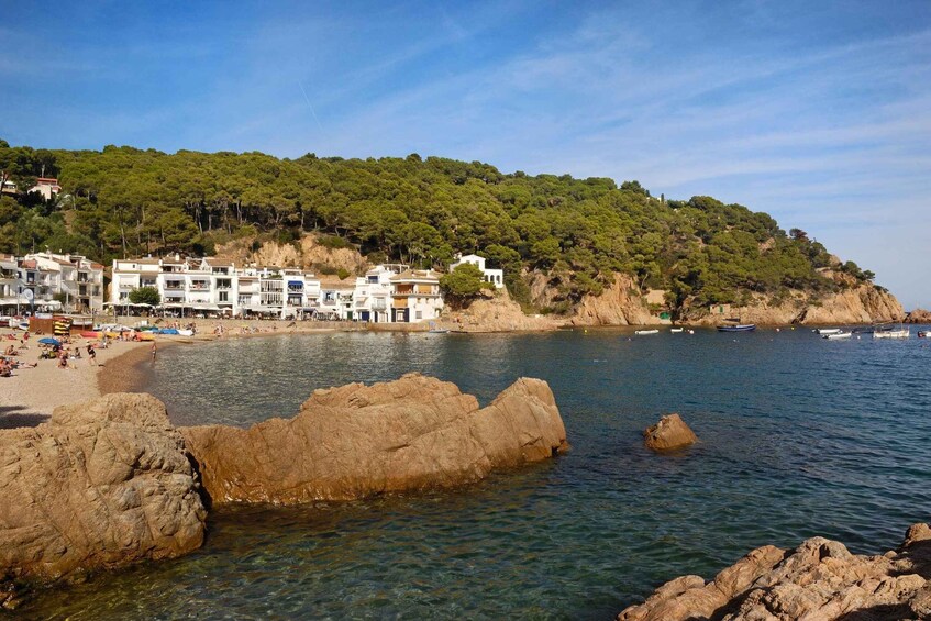 A coastal town with buildings on a hillside, a rocky shoreline, and boats in the water. 5