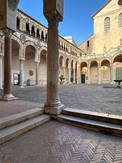 An ancient courtyard with arches, columns, and a tiled floor. 1
