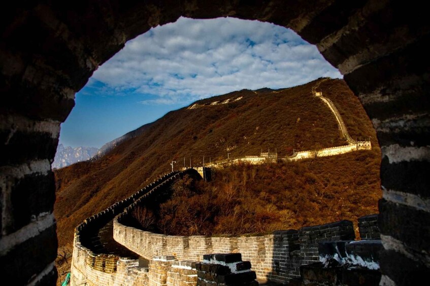 The Great Wall of China, a historic fortification, viewed through a natural archway. 2