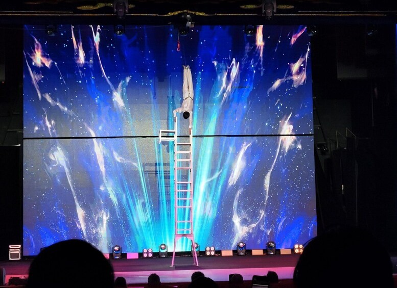 A stage with a large screen displaying a space-themed backdrop, a ladder, and a figure in a spacesuit. 2