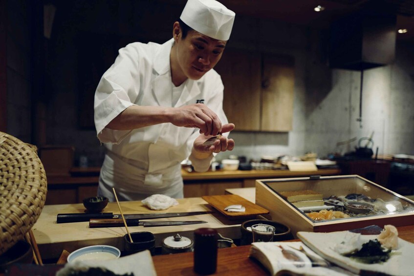 A chef preparing food in a kitchen with various cooking utensils and ingredients on the counter. 2