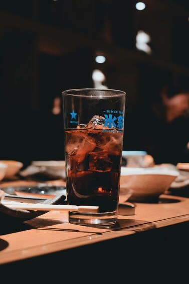 A glass of iced beverage with a blue star logo on a wooden table in a dimly lit setting. 5