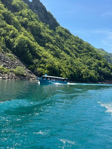 A boat on a turquoise river with lush green hills in the background. 5