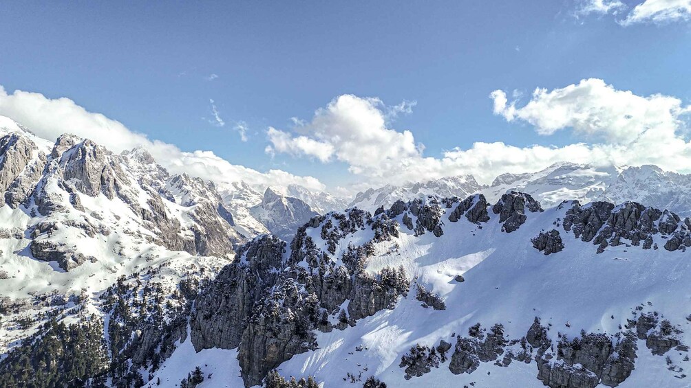 A snow-covered mountain range with rocky peaks and scattered trees. 3
